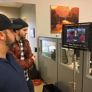 Two men standing in front of a television.