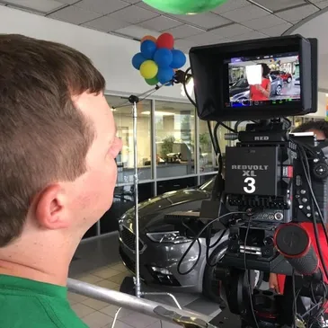 A man is filming a video of a car.