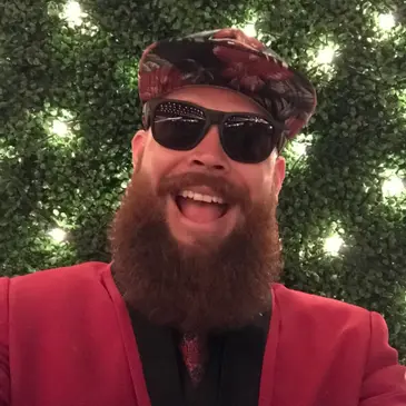 A man with a beard and sunglasses in front of a christmas tree.