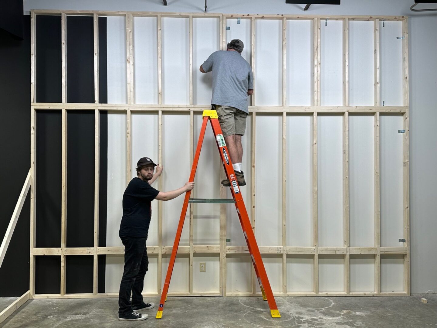 Two people are working on a wall.