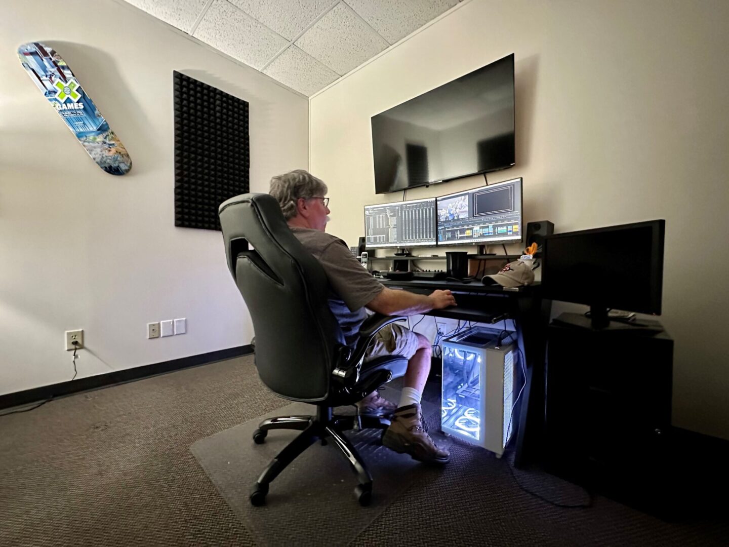 A man sitting at his computer desk in front of two monitors.