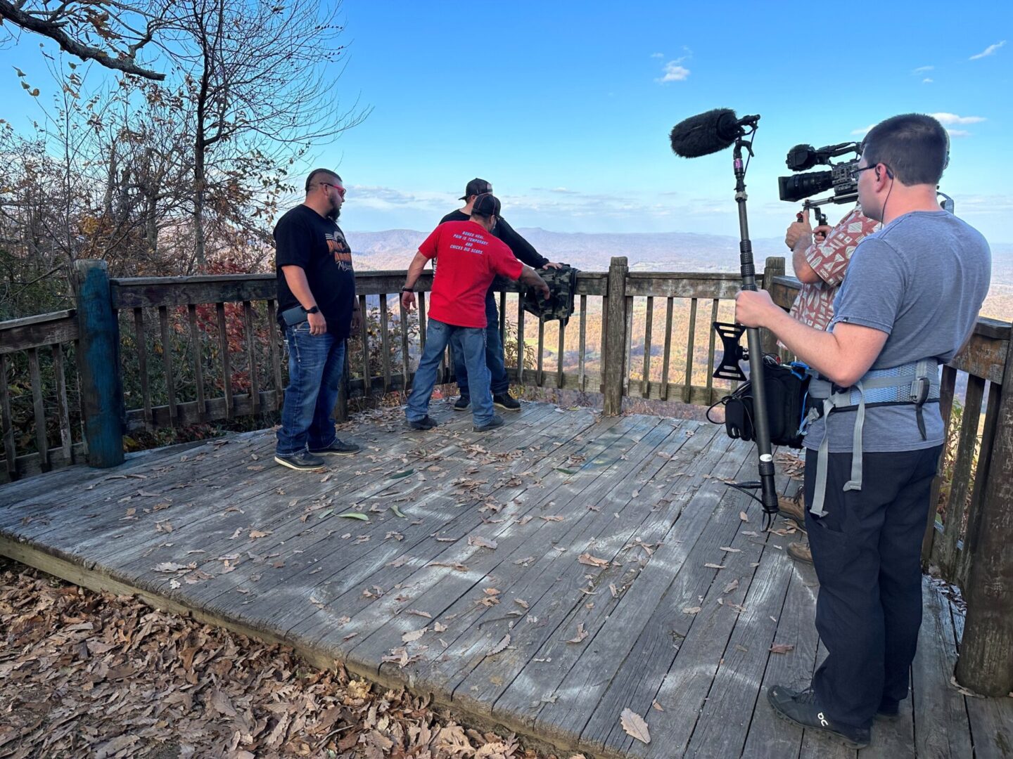 A group of people standing on top of a wooden deck.