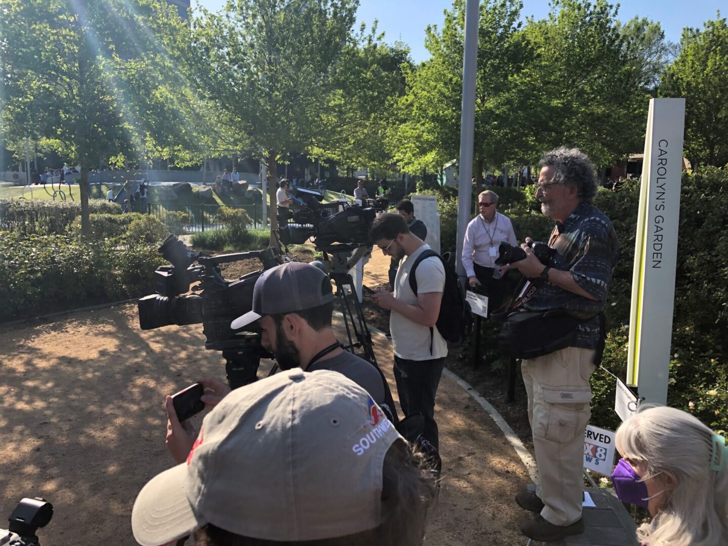 A group of people standing around in the sun.